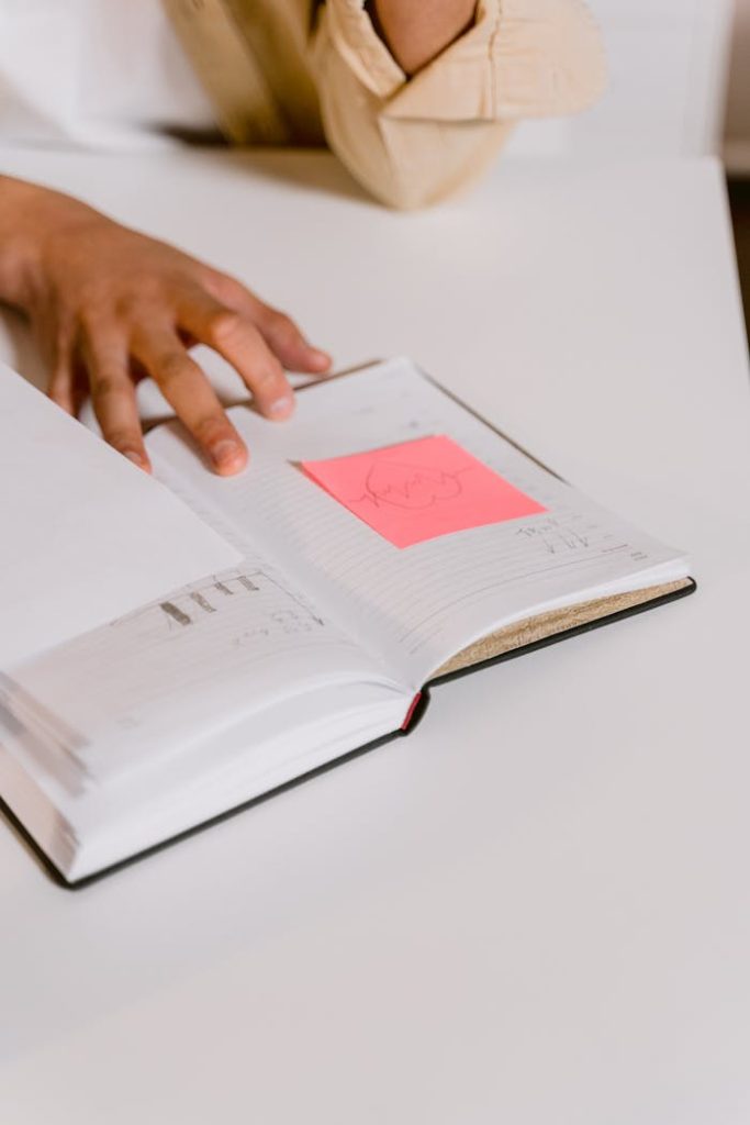 Open notebook with pink sticky notes for business planning on a desk.